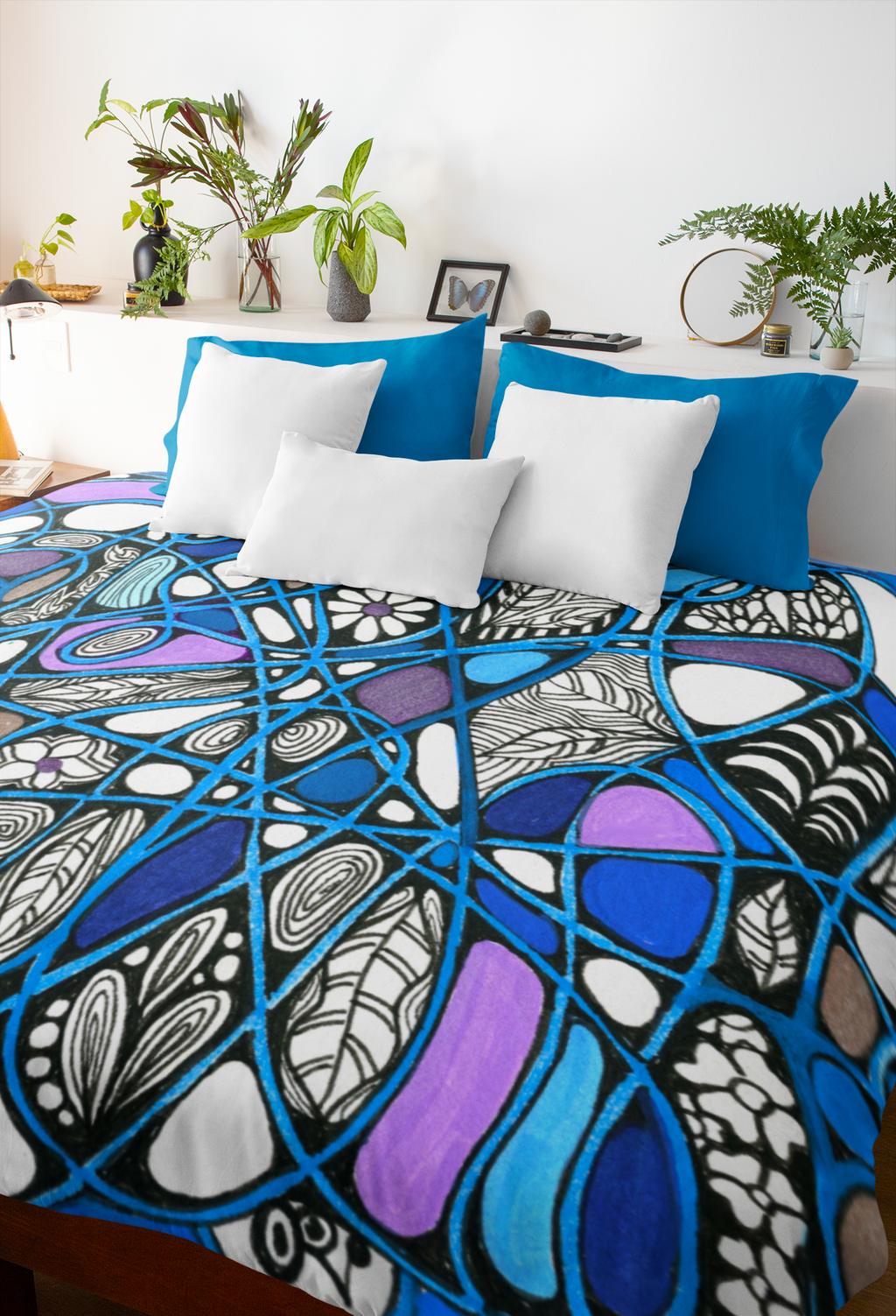 Bold abstract doodle art blanket in blue, purple, and black on a cozy bed with white and blue pillows